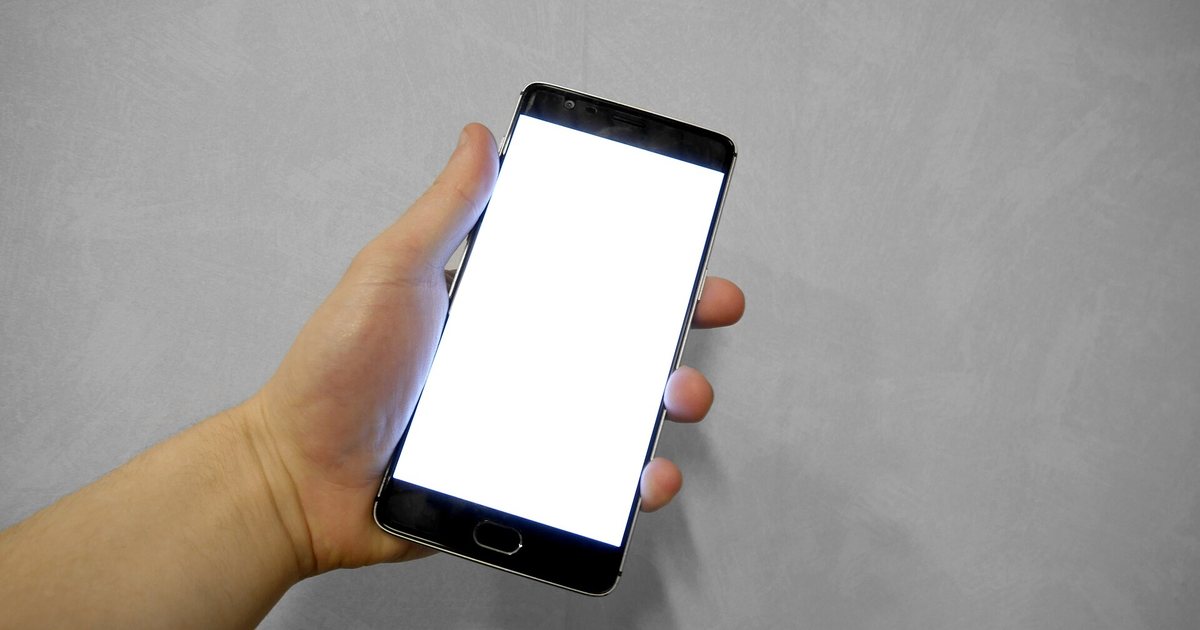 Una mano sostiene un teléfono celular con la pantalla en blanco
