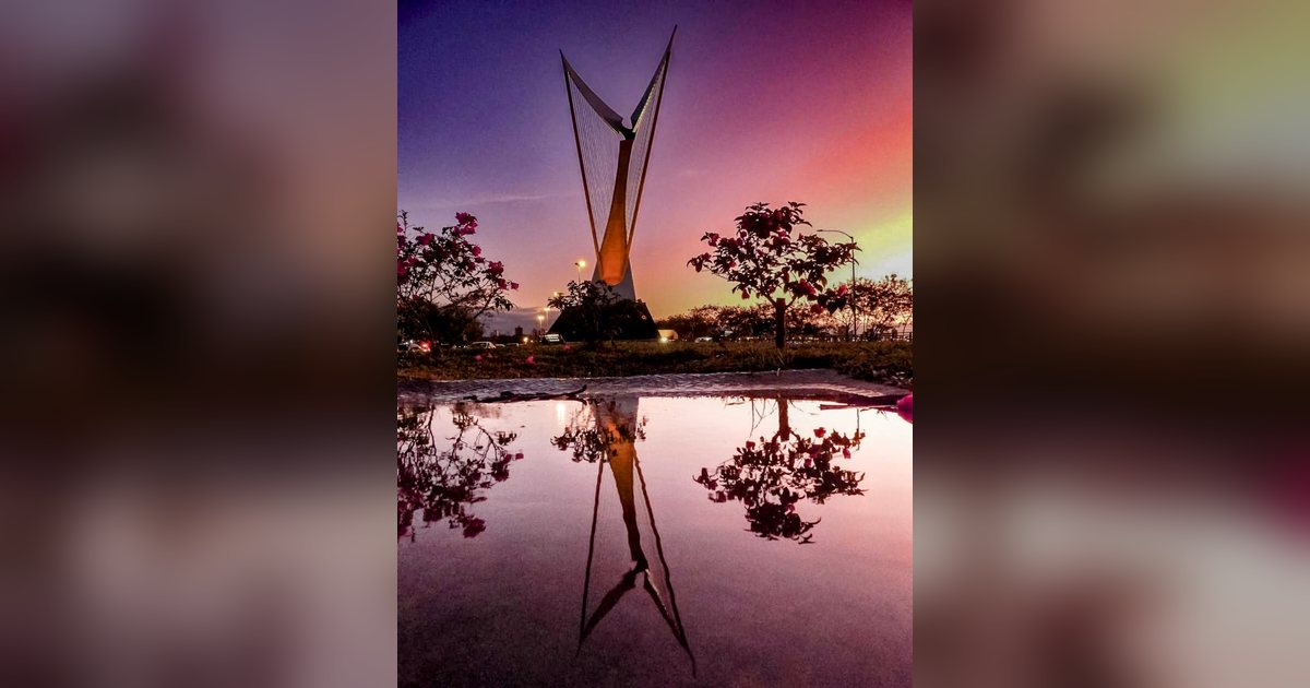 El monumento del arpa en la avenida Costanera de Asunción, al atardecer, reflejado en un charco