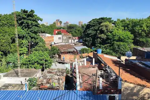 Techos y casas del barrio Ricardo Brugada, la Chacarita, en Asunción, con edificios del centro al fondo