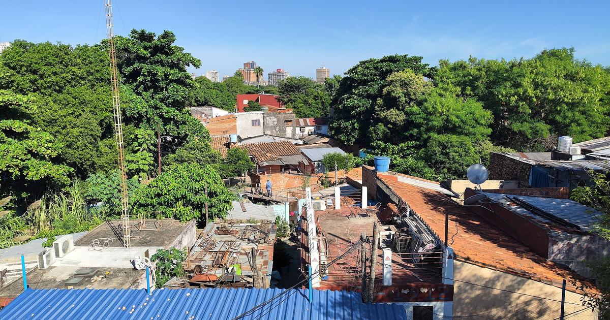 Techos y casas del barrio Ricardo Brugada, la Chacarita, en Asunción, con edificios del centro al fondo