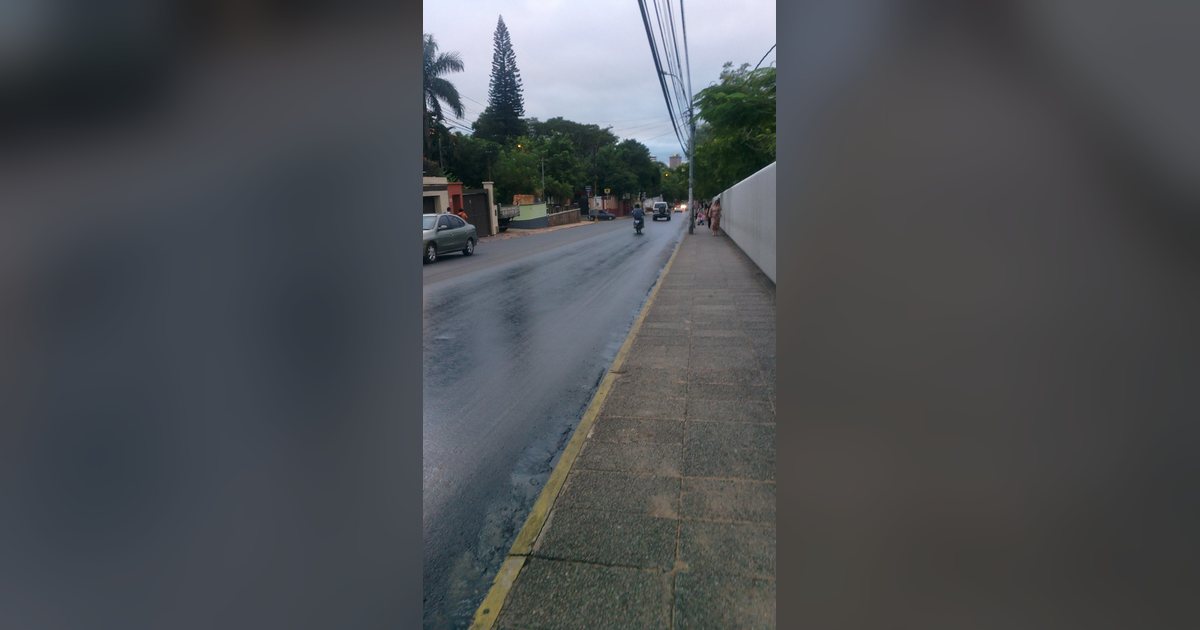 La avenida España de Asunción, mojada después de la lluvia, con autos y una moto a lo lejos