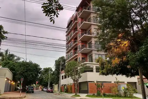 Calle residencial empedrada del barrio Carmelitas, en Asunción, con casas bajas y un edificio de departamentos