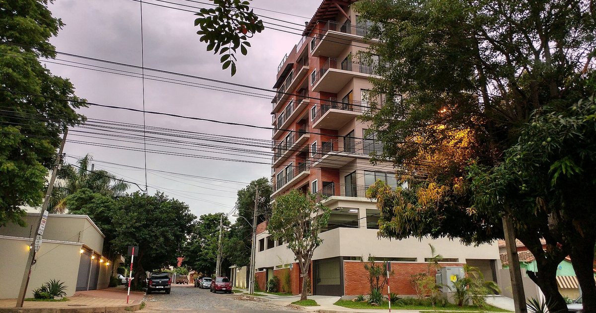 Calle residencial empedrada del barrio Carmelitas, en Asunción, con casas bajas y un edificio de departamentos