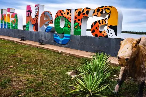 Letras de colores con el nombre de Bahía Negra, pintadas con un jaguar y aves, frente al río