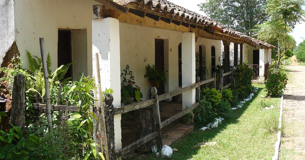Casa antigua de Caapucú con techo de tejas, galería sobre pilares blancos y un jardín junto a una calle empedrada