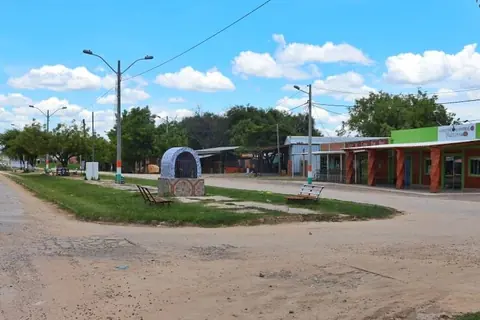 Calle del centro de Carmelo Peralta, con un cantero con bancos en el medio y comercios a un costado