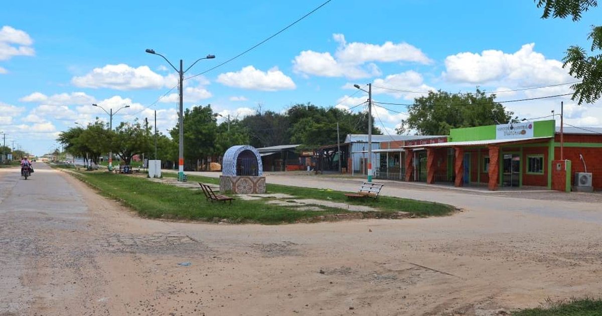 Calle del centro de Carmelo Peralta, con un cantero con bancos en el medio y comercios a un costado