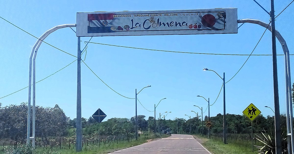 Arco de bienvenida de La Colmena sobre el ramal de acceso, con saludos en castellano, guaraní, inglés y japonés