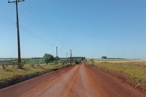 Camino de tierra roja entre campos de cultivo, sobre la avenida Japón, en Pirapó