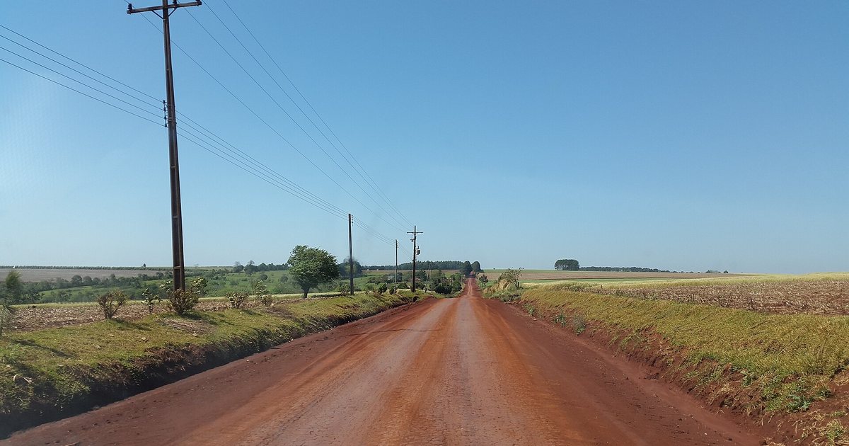 Camino de tierra roja entre campos de cultivo, sobre la avenida Japón, en Pirapó