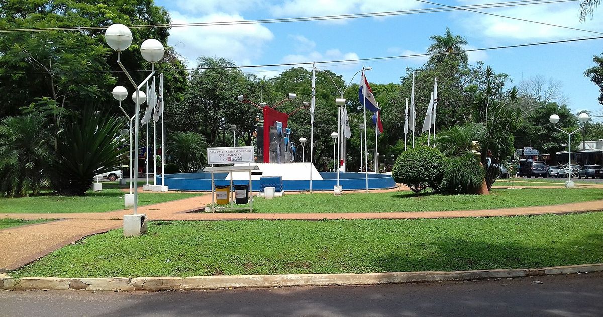 Plaza con mástiles, faroles y un monumento en el centro de Salto del Guairá
