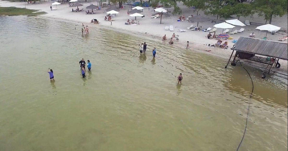 Bañistas en la orilla de arena blanca de la Laguna Blanca, en Santa Rosa del Aguaray