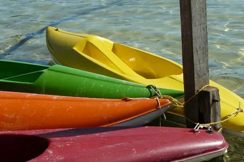Kayaks de colores amarrados a un poste de madera en el agua transparente de la Laguna Blanca