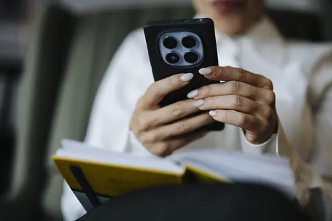 Foto: Shixart1985 / Wikimedia Commons · CC BY 2.0 Manos de una persona que usa el celular, con una libreta abierta sobre las piernas