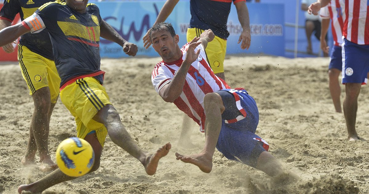 Un jugador de la selección paraguaya de fútbol playa se lanza por la pelota en la arena durante un partido