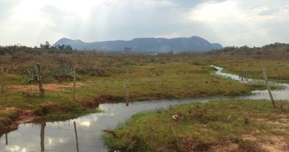 El cerro Acahay a lo lejos, visto desde un campo con un arroyo, en Paraguarí