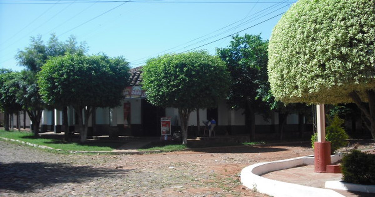 Calle Teniente Recalde, empedrada, con casas de galería y árboles, en Quiindy, Paraguarí