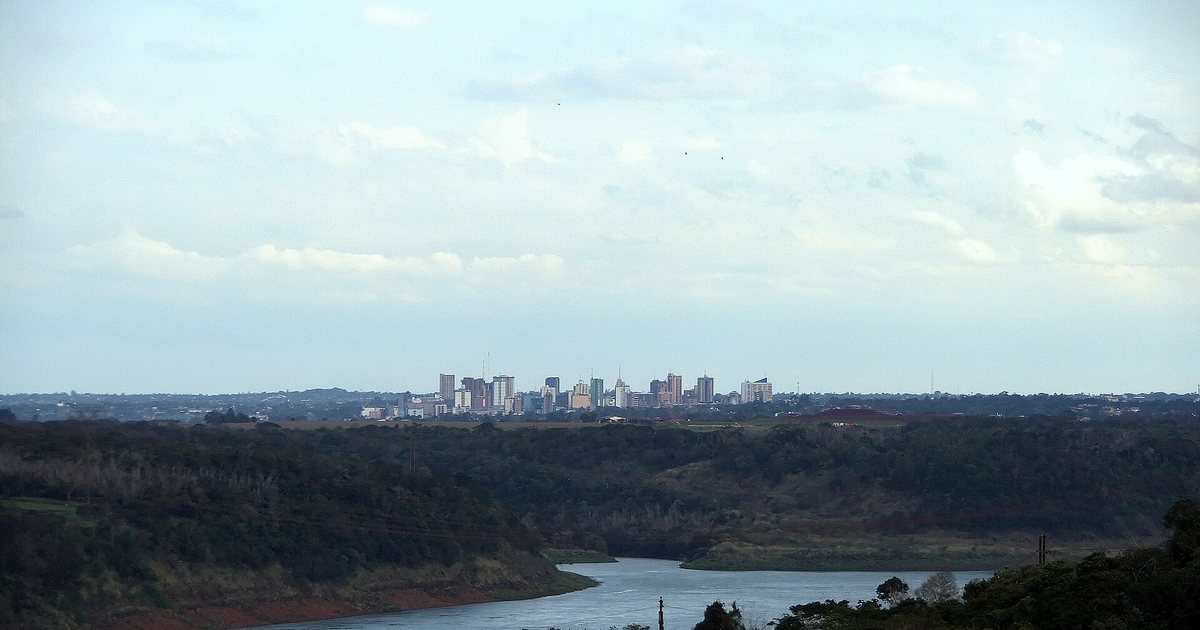 Los edificios de Ciudad del Este vistos a lo lejos desde Itaipú, con el río Paraná y el cielo nublado