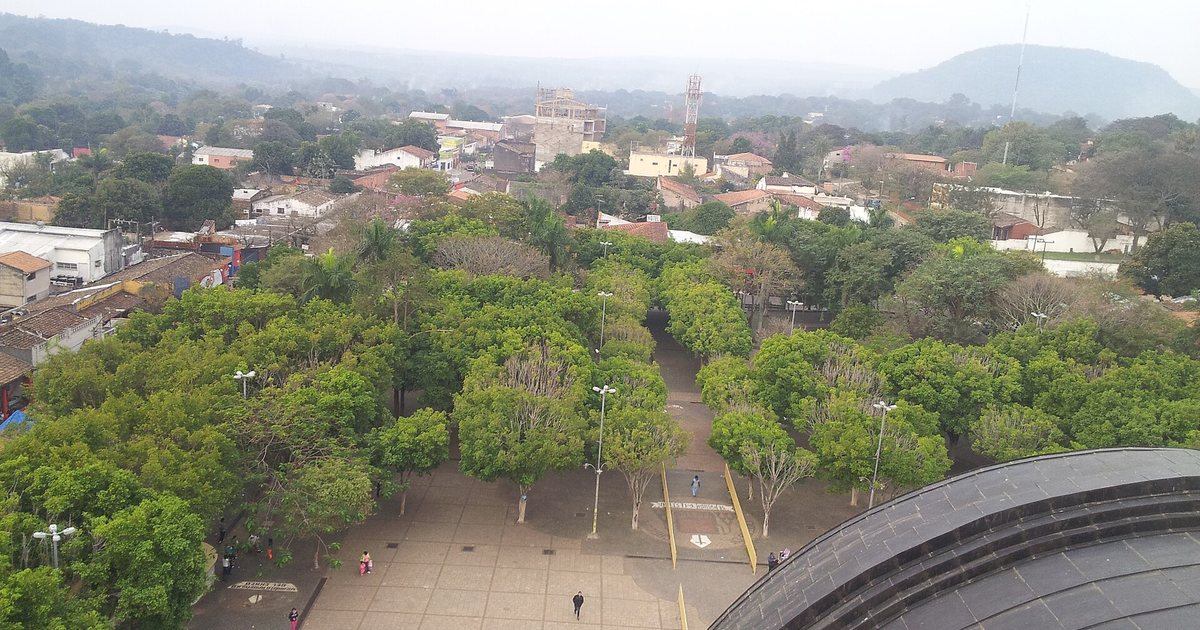 Explanada frente a la Basílica de Caacupé vista desde lo alto, con árboles, la ciudad y los cerros de la cordillera al fondo