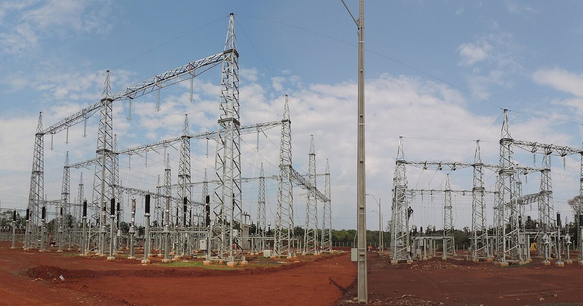 Torres y pórticos metálicos de la subestación Cambyretá de la ANDE, en construcción, sobre tierra roja y bajo un cielo con nubes