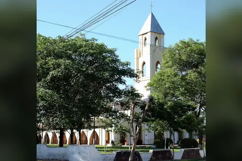 Foto: Cmasi / Wikimedia Commons · CC BY-SA 4.0 Iglesia blanca con campanario de techo a dos aguas y galería de arcos, detrás de árboles frondosos