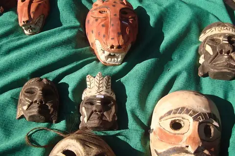 Foto: Mateuverte / Wikimedia Commons · CC BY-SA 3.0 Máscaras de madera talladas y pintadas, entre ellas una de jaguar y una con bigote, sobre una tela verde en Tobatí