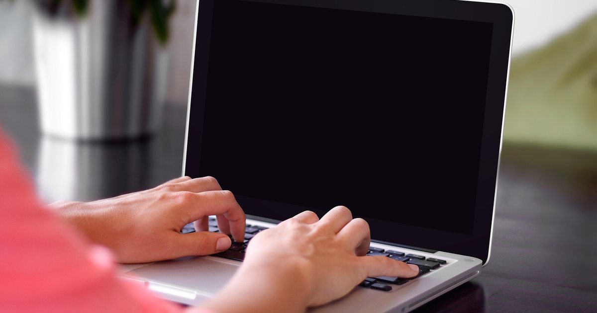 Manos que escriben en una computadora portátil, como al cargar la planilla de salarios en línea