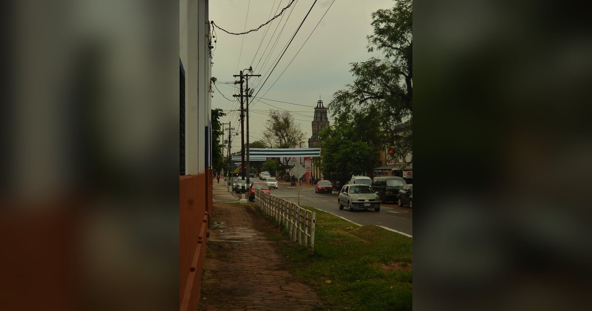 Calle del centro de Ypacaraí con la torre de la iglesia parroquial al fondo, en el departamento Central